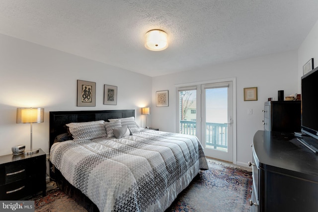 bedroom featuring access to exterior, a textured ceiling, and baseboards