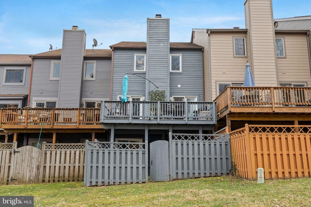 back of property featuring a gate, fence, a deck, and a lawn