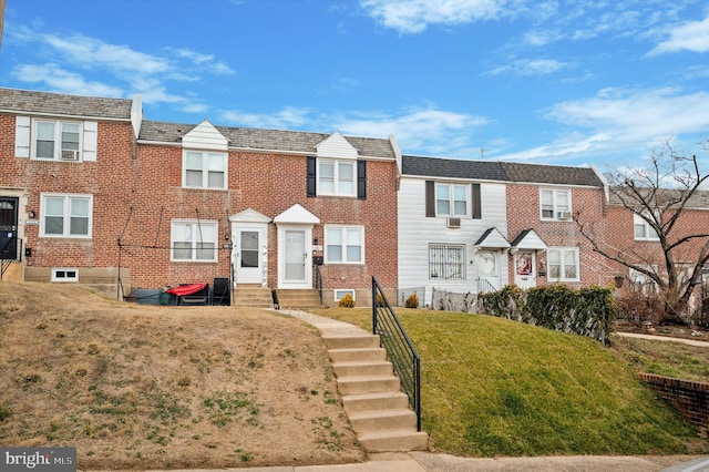 townhome / multi-family property with entry steps, a front yard, and brick siding