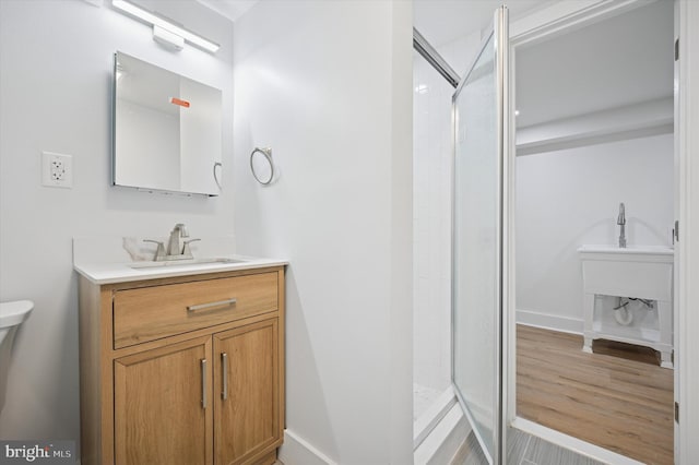 full bathroom featuring a shower stall, vanity, baseboards, and wood finished floors