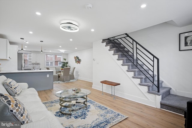 living room featuring light wood finished floors, stairway, and recessed lighting