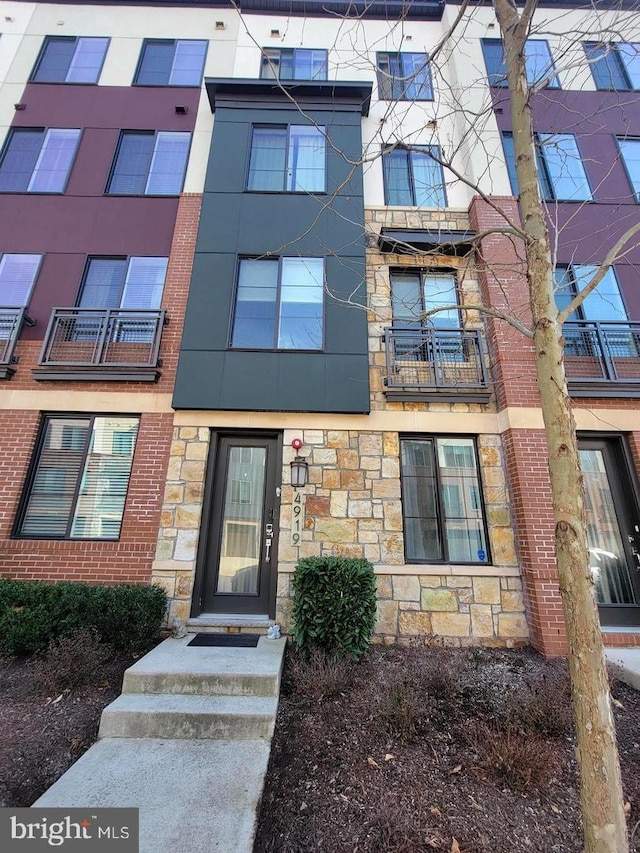 view of exterior entry featuring stone siding and brick siding