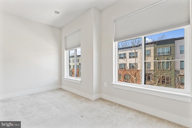 spare room with carpet, visible vents, and baseboards