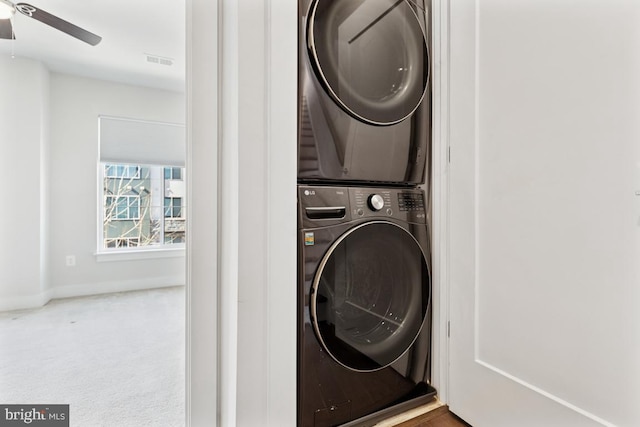 laundry room featuring laundry area, visible vents, baseboards, stacked washer and clothes dryer, and ceiling fan