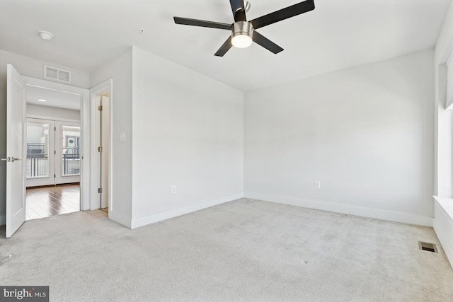 spare room featuring carpet, visible vents, ceiling fan, and baseboards