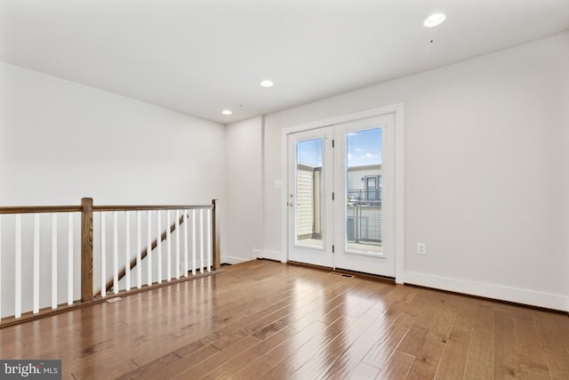 spare room featuring baseboards, wood finished floors, and recessed lighting