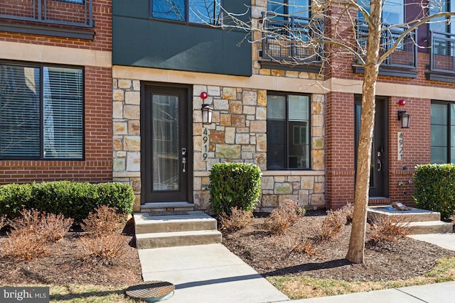 view of exterior entry with stone siding and brick siding