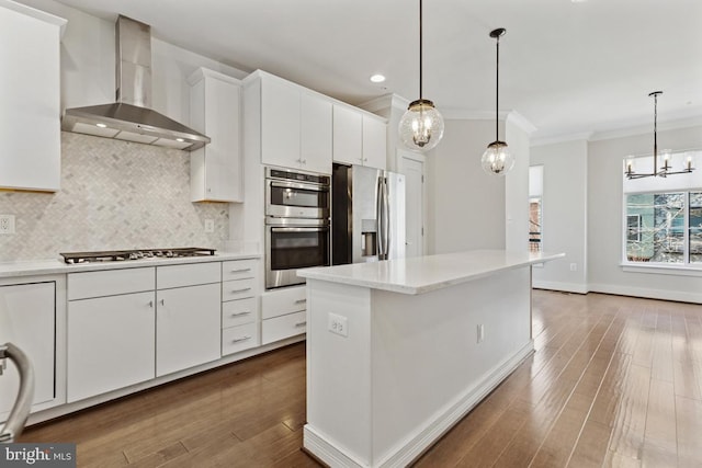 kitchen with stainless steel appliances, tasteful backsplash, ornamental molding, white cabinets, and wall chimney exhaust hood