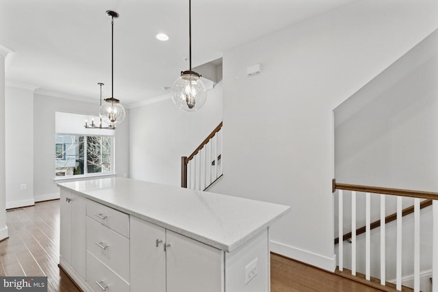 kitchen with crown molding, light countertops, white cabinetry, wood finished floors, and baseboards