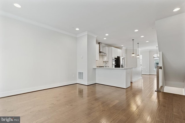 unfurnished living room with crown molding, a notable chandelier, visible vents, light wood-style flooring, and a sink