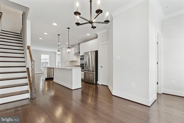 kitchen featuring dark wood-style flooring, white cabinets, stainless steel refrigerator with ice dispenser, an island with sink, and crown molding