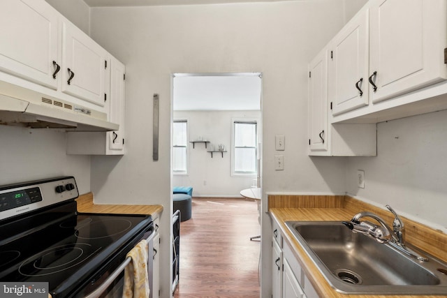 kitchen with light countertops, white cabinets, stainless steel range with electric cooktop, a sink, and under cabinet range hood