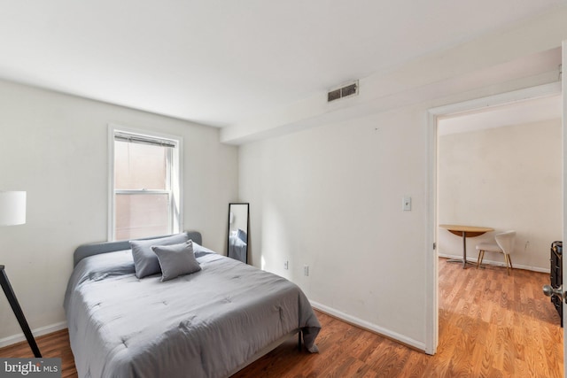 bedroom featuring light wood finished floors, baseboards, and visible vents