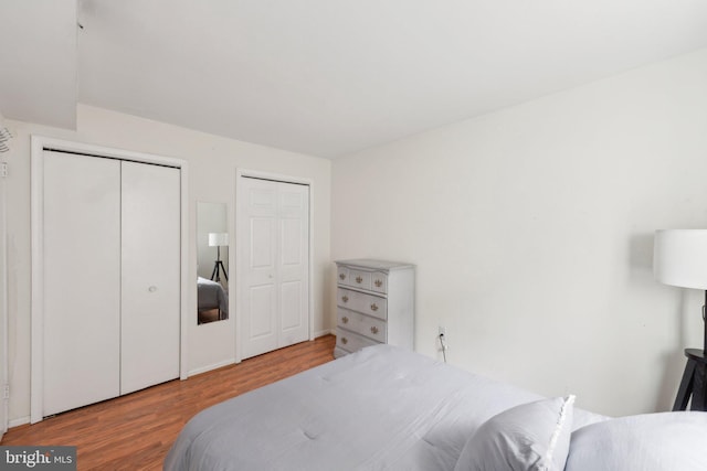 bedroom featuring multiple closets and wood finished floors