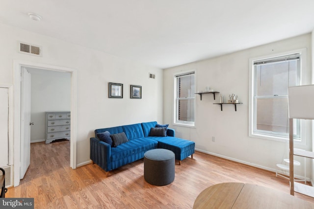 living room featuring light wood-style floors, baseboards, and visible vents