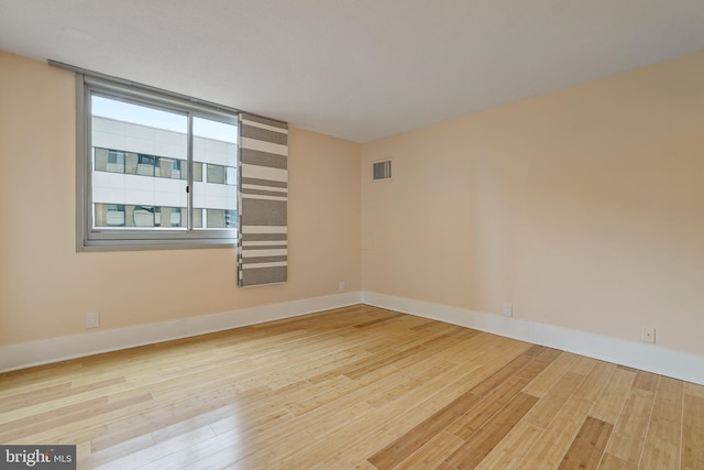 empty room featuring visible vents, baseboards, and wood finished floors