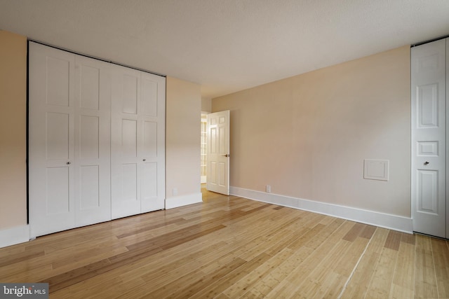 unfurnished bedroom featuring light wood-type flooring, baseboards, and a closet