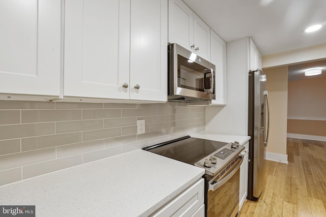 kitchen featuring backsplash, white cabinets, stainless steel appliances, and light wood-type flooring