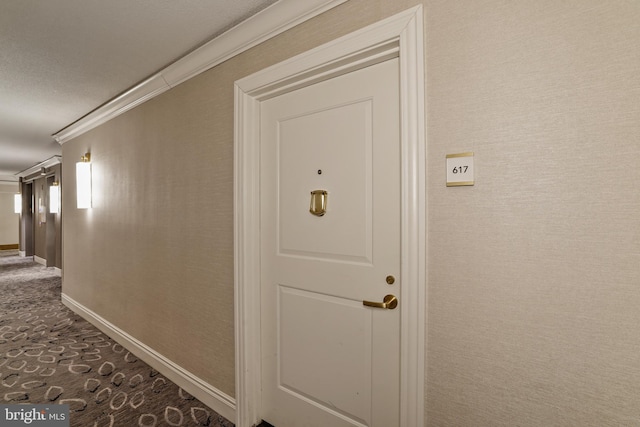 hallway with dark colored carpet, baseboards, and ornamental molding