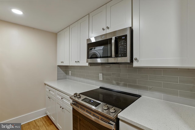 kitchen featuring stainless steel appliances, backsplash, and white cabinetry