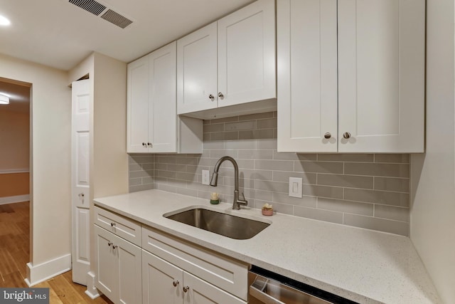 kitchen featuring white cabinets, light wood-style floors, visible vents, and a sink