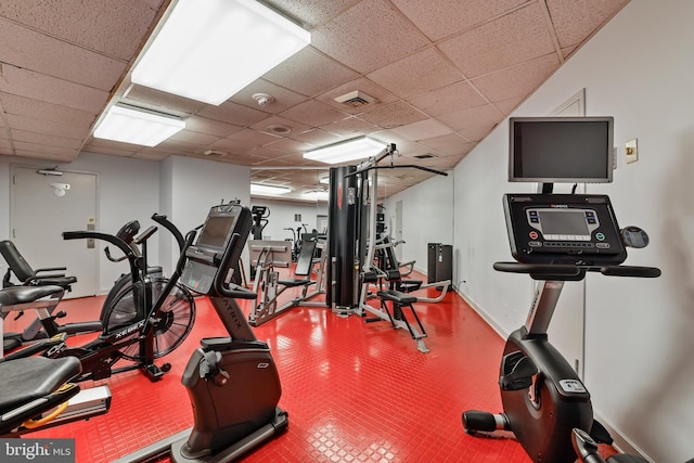 gym with visible vents, a paneled ceiling, and baseboards