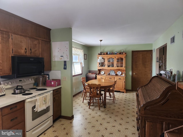 kitchen with black microwave, visible vents, light countertops, white range with electric stovetop, and glass insert cabinets