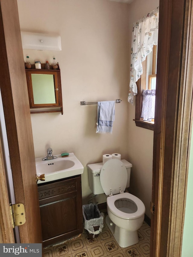 half bathroom with tile patterned flooring, vanity, and toilet