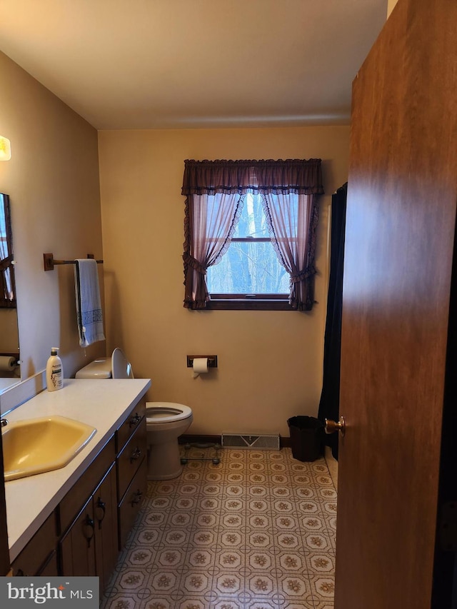 bathroom featuring baseboards, visible vents, toilet, tile patterned floors, and vanity