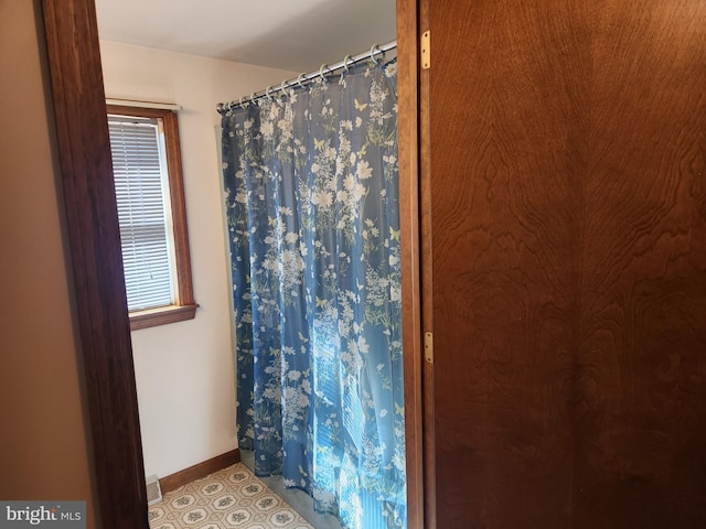 bathroom featuring a shower with shower curtain, tile patterned floors, visible vents, and baseboards