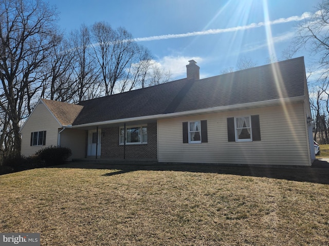 ranch-style house with a front lawn, a chimney, a shingled roof, and brick siding