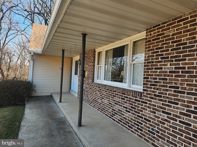 exterior space featuring a porch, brick siding, and roof with shingles