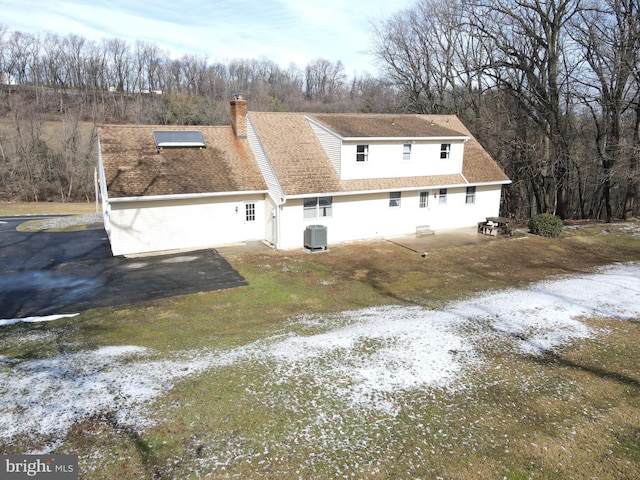 exterior space featuring a shingled roof, a chimney, central AC, and a patio