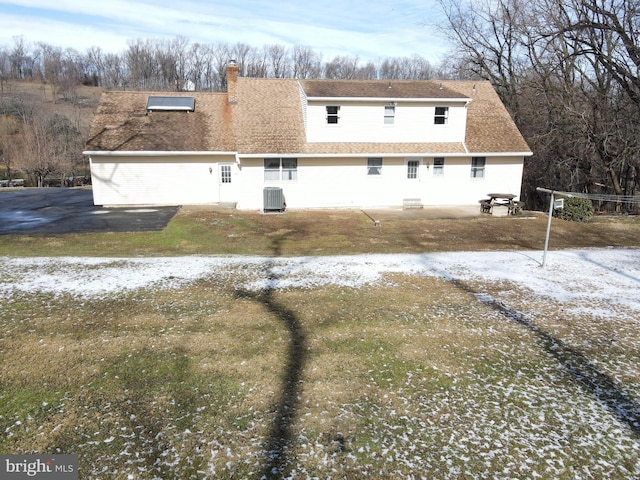 rear view of property featuring a shingled roof, a chimney, and central air condition unit