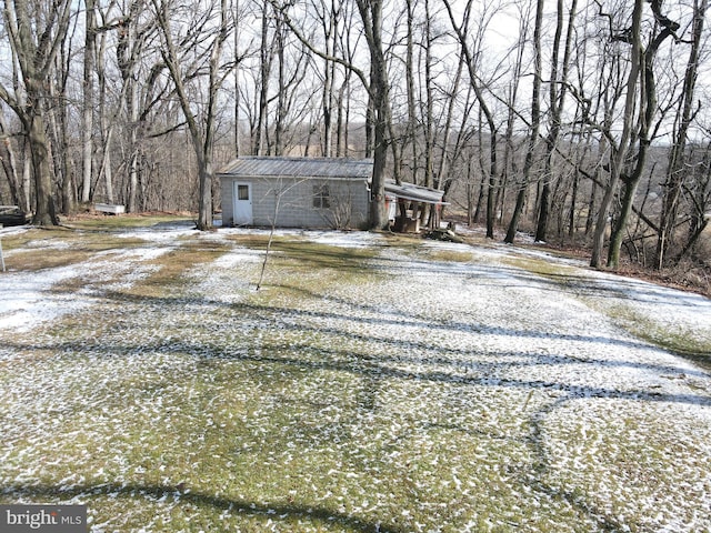 view of front facade with metal roof, gravel driveway, and a wooded view