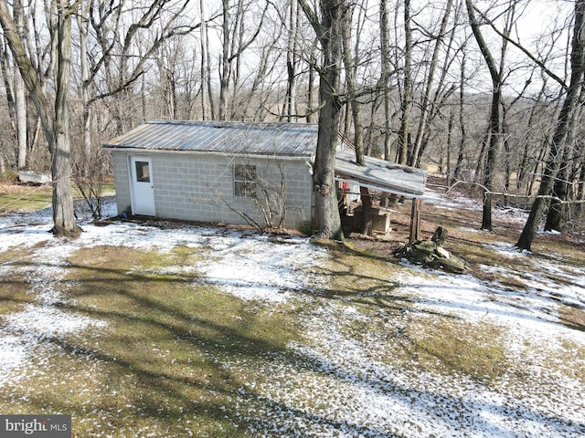 exterior space with an outbuilding, concrete block siding, and metal roof