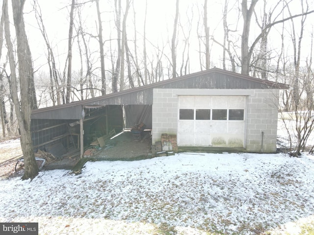 snow covered garage featuring driveway and a detached garage