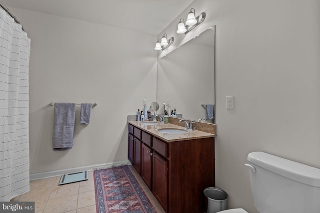 bathroom featuring toilet, double vanity, a sink, and tile patterned floors