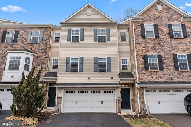 multi unit property featuring an attached garage and aphalt driveway