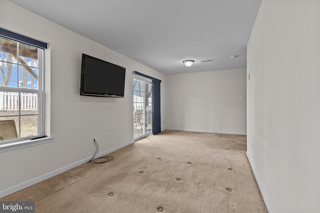 spare room featuring baseboards and light colored carpet