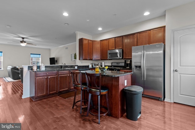 kitchen with stainless steel appliances, dark wood-type flooring, a peninsula, and a kitchen island