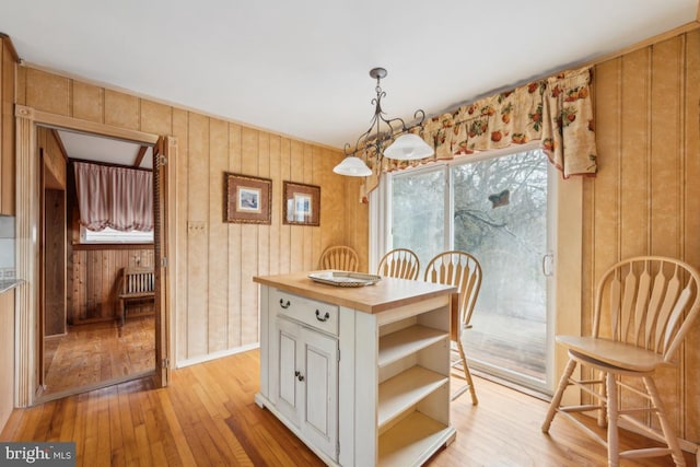 dining room with wooden walls and light wood-style flooring