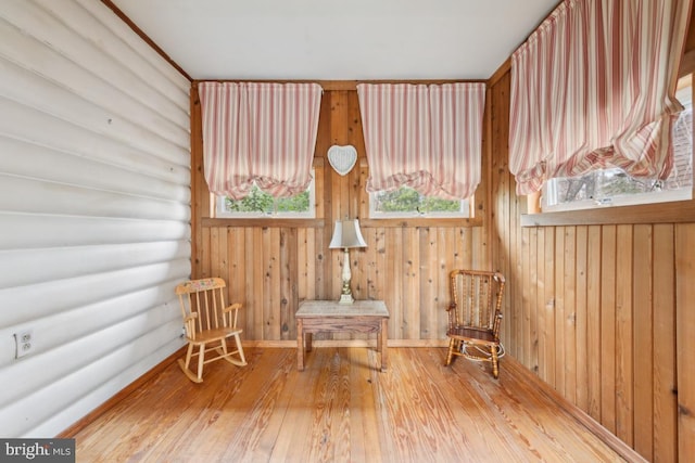 unfurnished room with log walls, hardwood / wood-style flooring, and baseboards