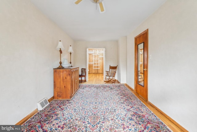 sitting room with light wood-style floors, baseboards, visible vents, and a ceiling fan