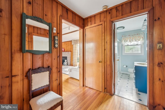 corridor featuring wood walls, a sink, and light wood-style floors