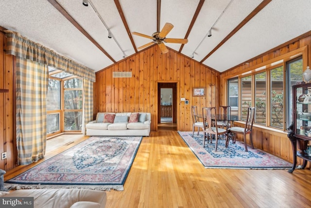 living area featuring hardwood / wood-style flooring, plenty of natural light, visible vents, and vaulted ceiling