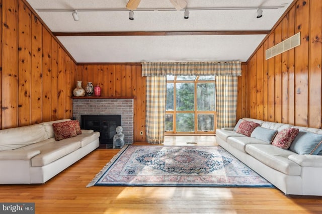 living room with lofted ceiling with beams, a fireplace, wood finished floors, and visible vents