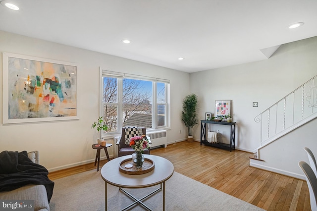 living area featuring hardwood / wood-style floors, recessed lighting, radiator, baseboards, and stairs