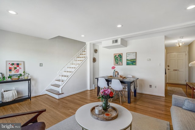 living area featuring recessed lighting, visible vents, wood finished floors, and stairs