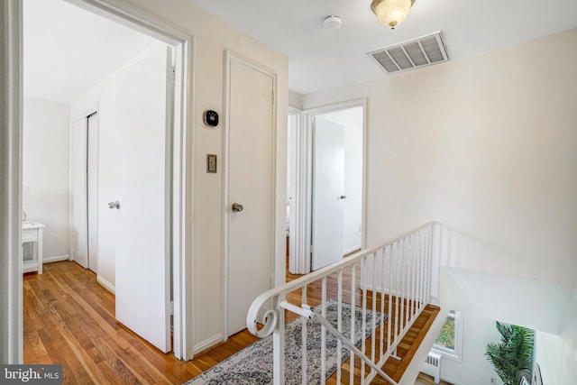 corridor with visible vents, an upstairs landing, and light wood-style flooring